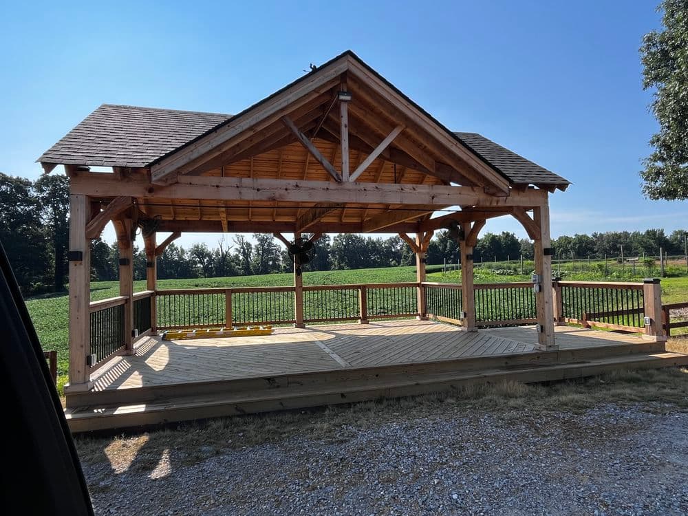 Rustic wooden pavilion in a field, perfect for outdoor events and gatherings.