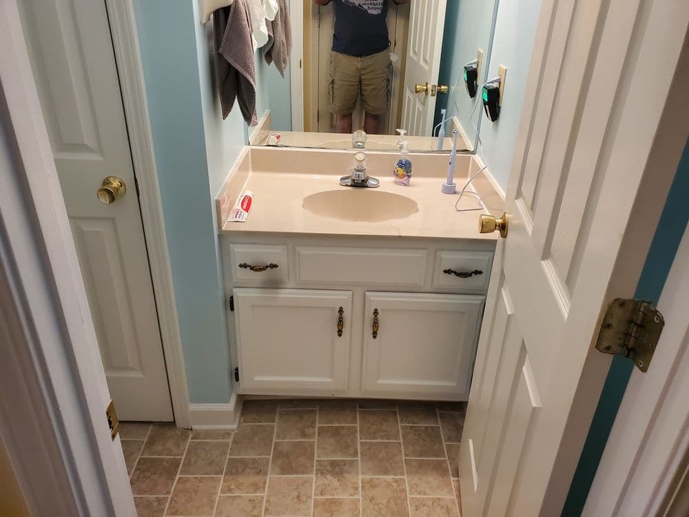 Modern bathroom with white cabinet, countertop sink, and light blue walls. Clean and organized space.