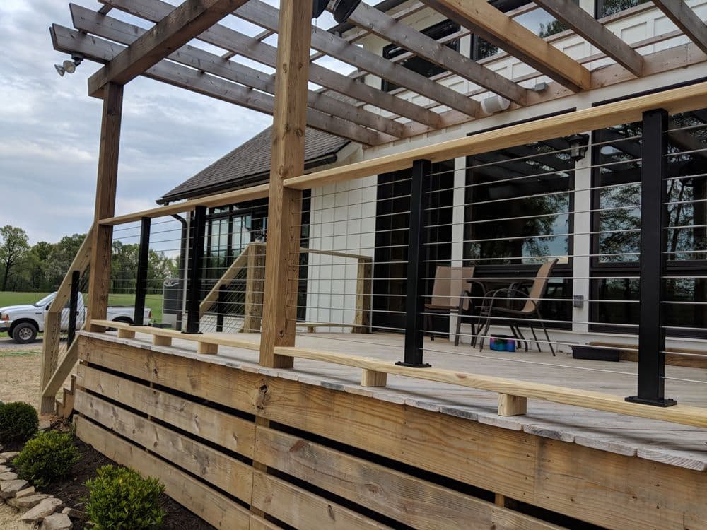 Modern wooden deck with railing and seating area, featuring a landscaped garden view.