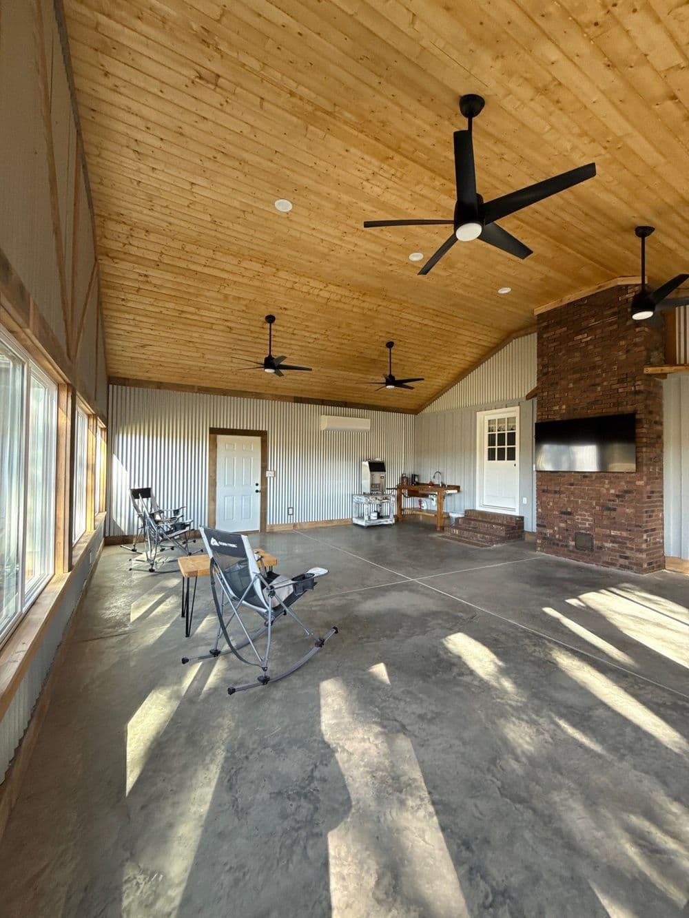 Spacious interior of a modern, rustic room with wooden ceiling and brick fireplace.